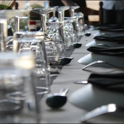Detalle de mesa en KOLI con copas de cristal invertidas, servilletas negras y cubiertos elegantes, preparada para un servicio especial.