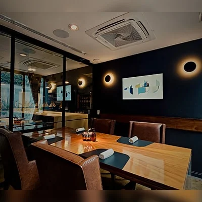 Sala privada en KOLI, con una mesa de madera elegante, iluminación cálida y detalles minimalistas que crean un ambiente íntimo ideal para experiencias gastronómicas personalizadas.
