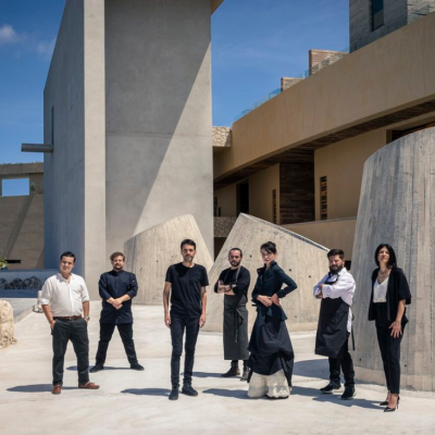 A culinary team posing at Casa de la Playa, with contemporary architecture in the background, reflecting culinary innovation and collaboration.