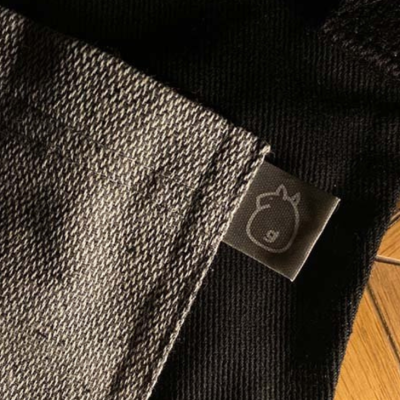 Fabric label featuring a minimalist horse logo, sewn onto the hem of a KOLI uniform.