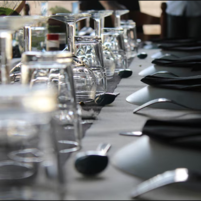 koli-detalle-mesa-servicio-evento.jpg A table setting at KOLI featuring inverted crystal glasses, black napkins, and elegant cutlery, prepared for a special occasion.
