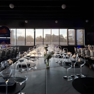 koli-catering-eventos An elegantly set long table with wine glasses and floral arrangements in KOLI's catering area